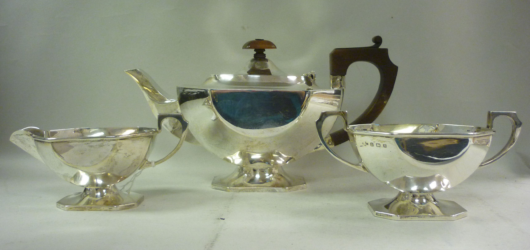 A three piece Art Deco silver tea set of elongated, panelled design comprising a teapot with a fibre