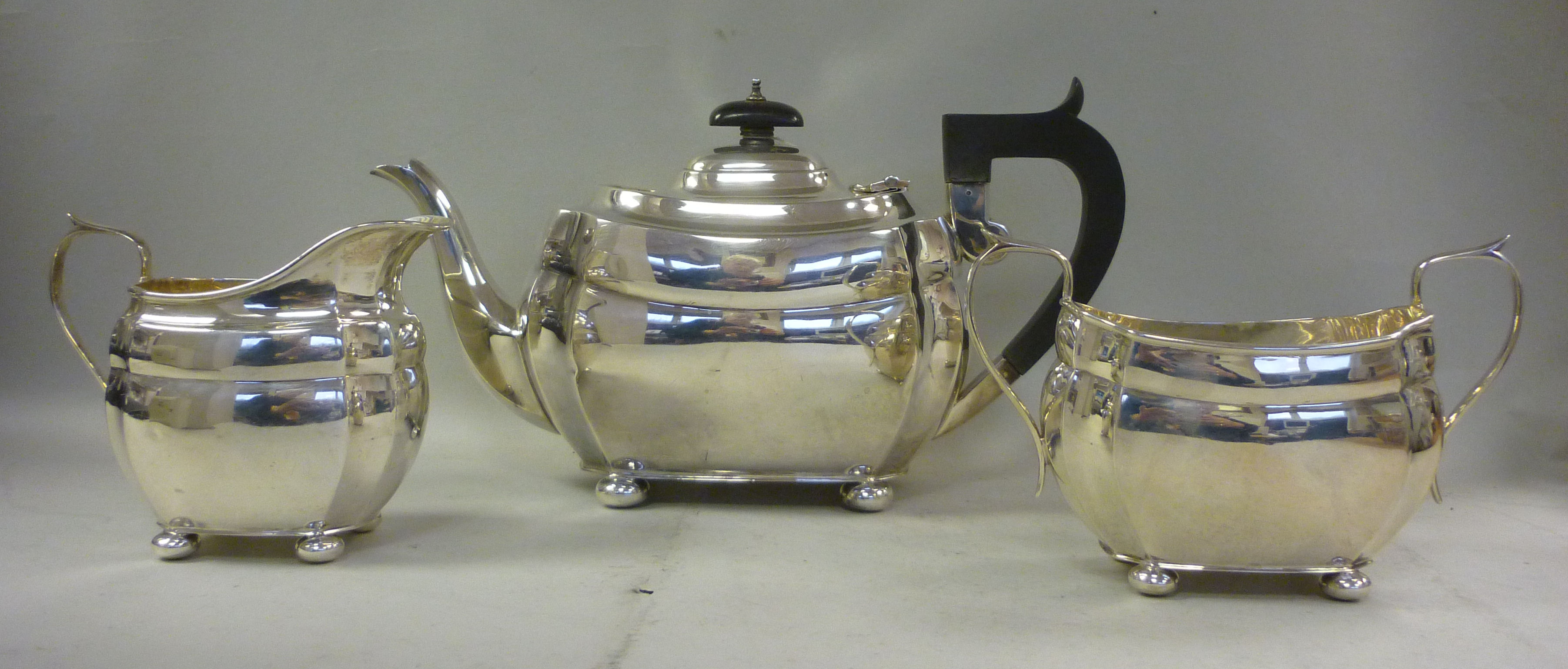 A three piece silver tea set of bulbous oval design with incurved corners, on button feet comprising