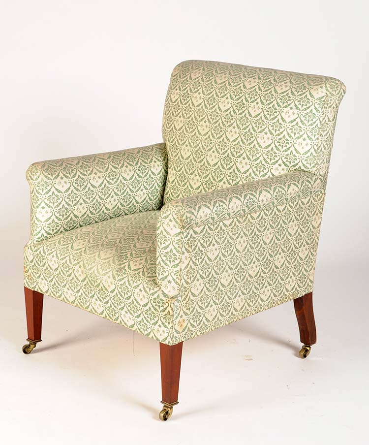 †  An Edwardian easy chair, by Howard & Sons Ltd., with original green printed upholstery bearing