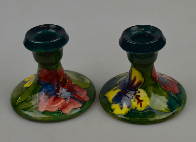 Two Moorcroft 'Hibiscus' pattern short candlesticks bearing paper label 'Potters to the late Queen