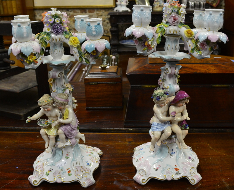 A pair of Continental porcelain four-branch candelabra encrusted overall with flowers, the pedestals