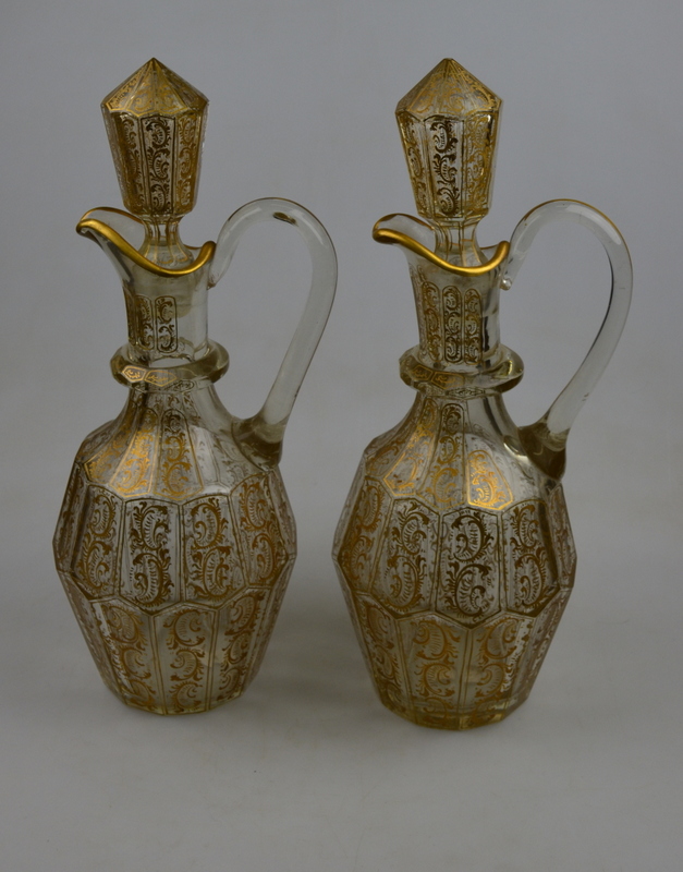 A pair of 19th century Bohemian faceted wine ewers and stoppers decorated overall with gilt