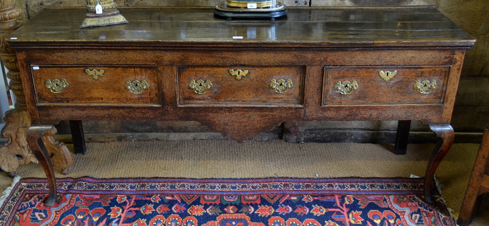 An 18th century oak low dresser, Midlands, the wide two plank top over a deep frieze with three