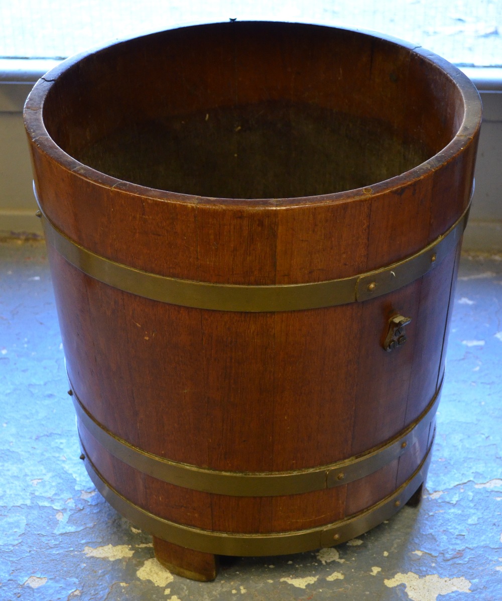 A 19th century brass bound coopered mahogany bucket raised on four straight-through stave feet,