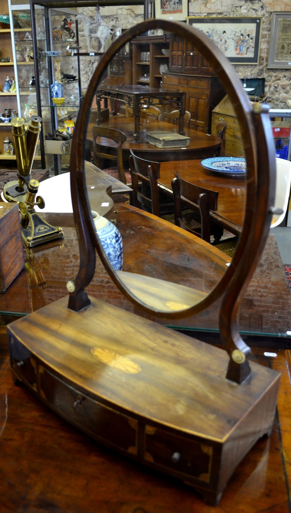 A 19th century mahogany toilet mirror with boxwood inlay raised on bowfront base with three drawers