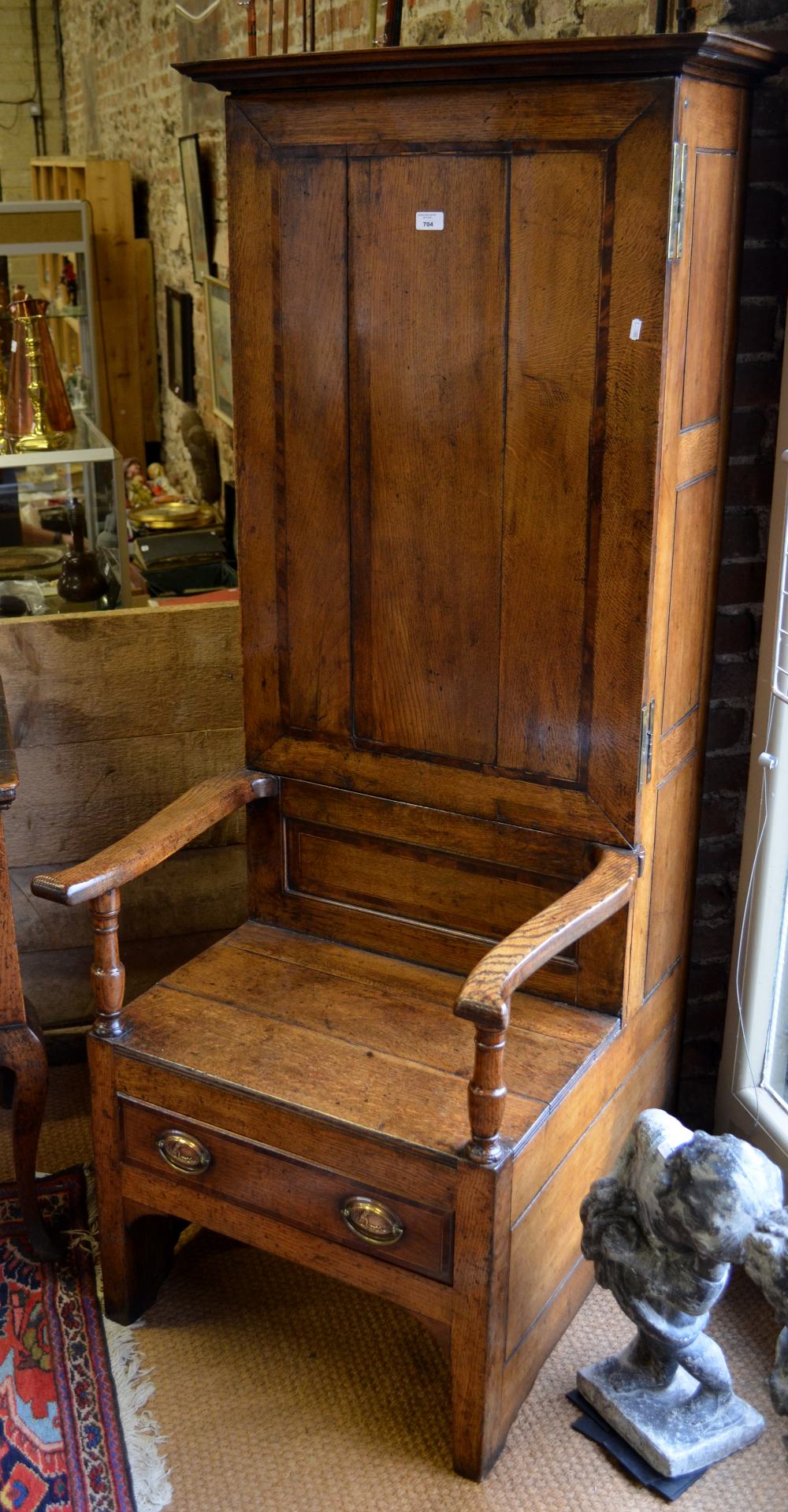 An 18th century mahogany cross-banded oak bacon settle, the tall cupboard back over long shaped arms