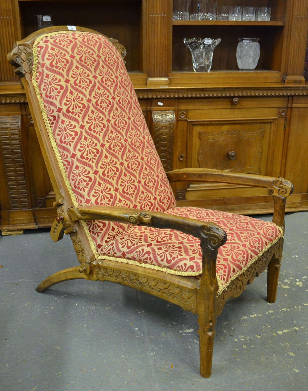 An Aesthetic period mahogany framed library armchair, the well carved frame with gothic style