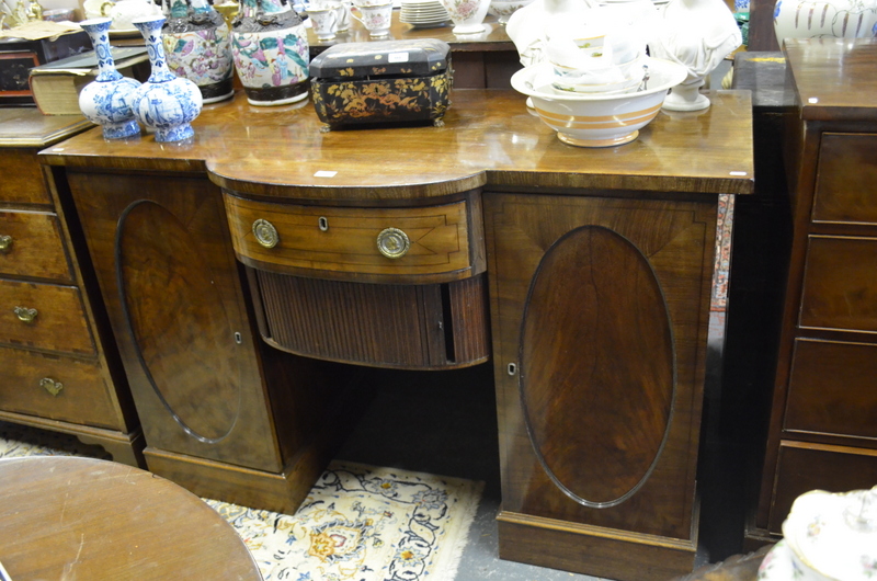 A Regency mahogany bowfront pedestal sideboard, centred with a drawer over a tambour cupboard,