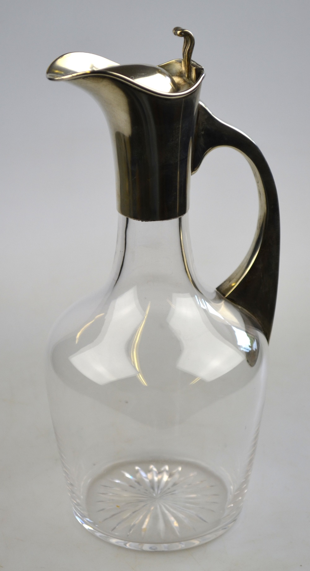 An Edwardian glass claret jug with star-cut base and silver collar, handle and hinged cover, J.