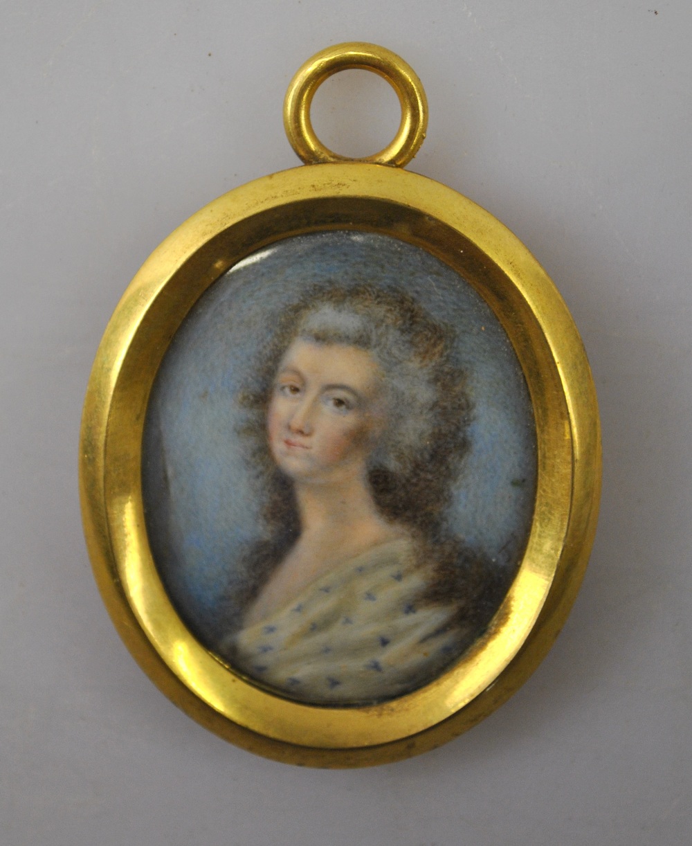 A Georgian oval portrait miniature of a lady with undressed hair and spotted shawl, 3.5 cm x 3 cm