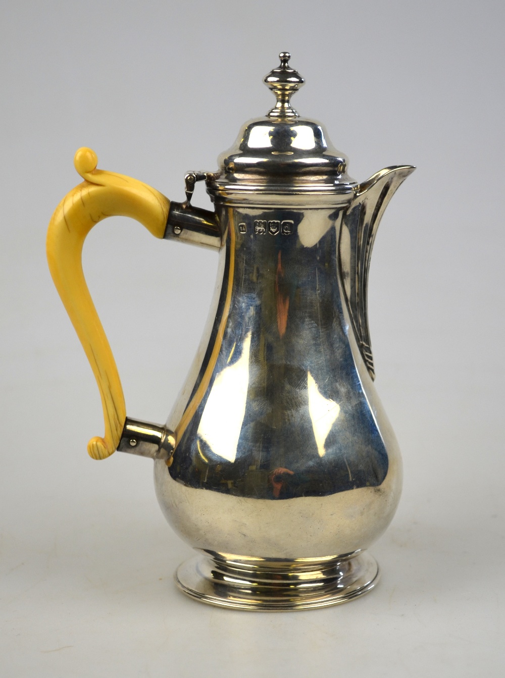 A late Victorian silver pear-shaped hot milk jug in the Georgian manner with carved ivory handle,