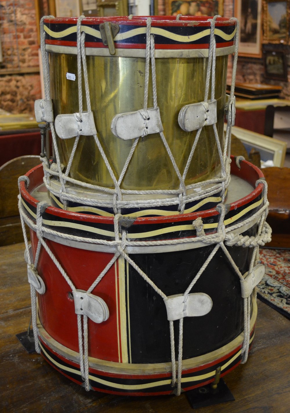 A brass military drum with painted wood frame 38 cm, to/w a similar wooden drum, 52 cm