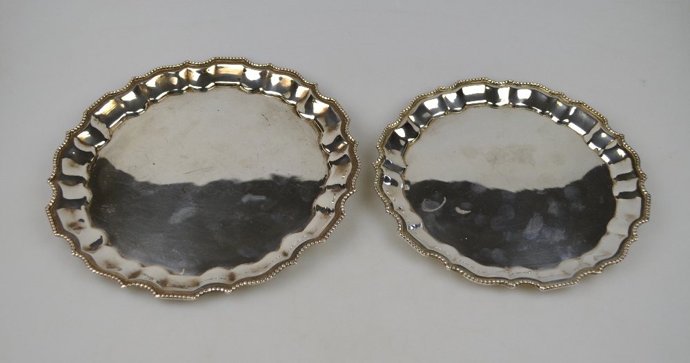 A graduated pair of pie-crust letter salvers with beaded rims, stamped '925', 21 and 18 cm