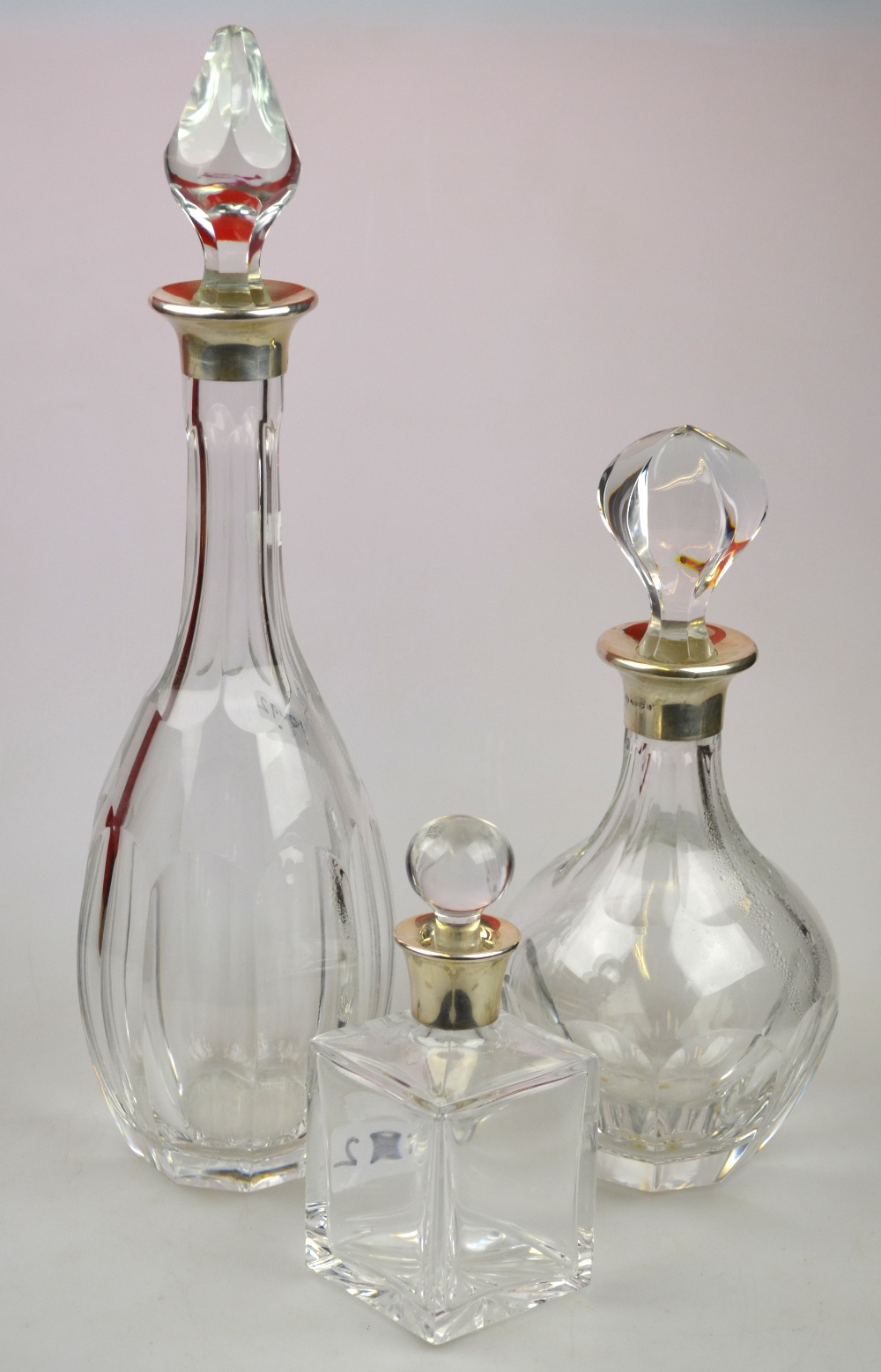 Two cut glass decanters and stoppers and a small square decante and stopper, all with flared