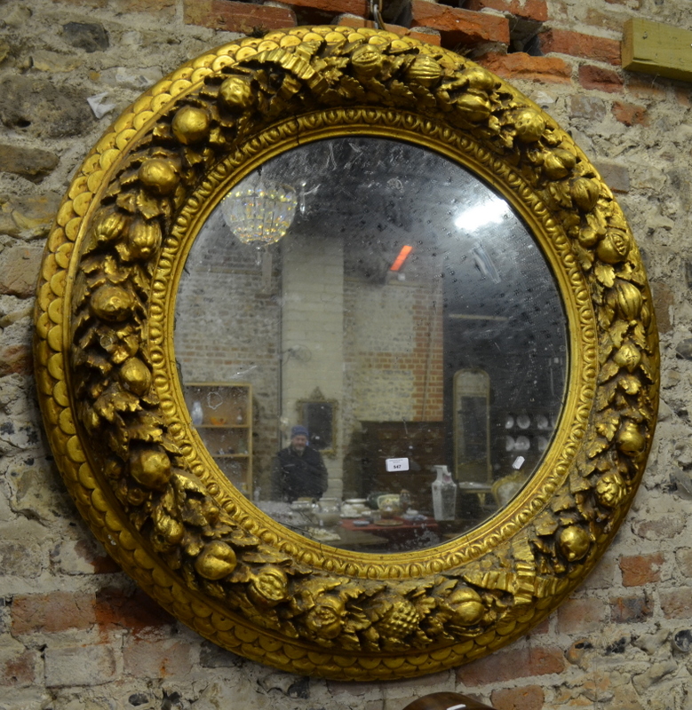 An oversize 19th century giltwood circular wall mirror, heavily decorated around the circumference