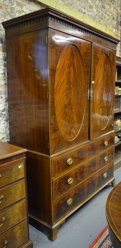 A 19th century inlaid flame mahogany linen press, the arcade moulded cornice over a pair of oval