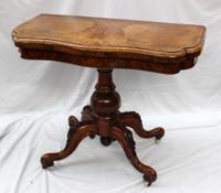 A Victorian walnut card table, the shaped inlaid top enclosing a baize interior above a shallow