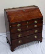 A 19th century mahogany bureau with a three quarter brass gallery and sloping fall enclosing a