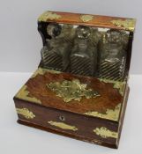 An oak tantalus, the three decanters enclosed by two lidded compartments, with brass mounts, 31.5 cm