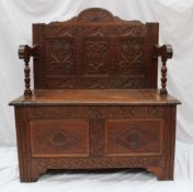 A 19th century carved oak box settle, the three panelled back above a box base with two panels on