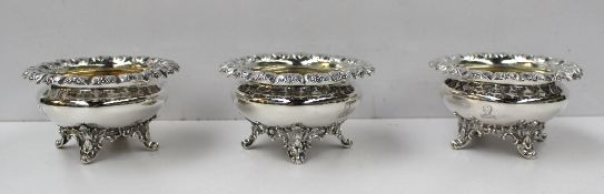 A set of three Victorian silver open table salts, the leaf and floral raised edge above a bulbous