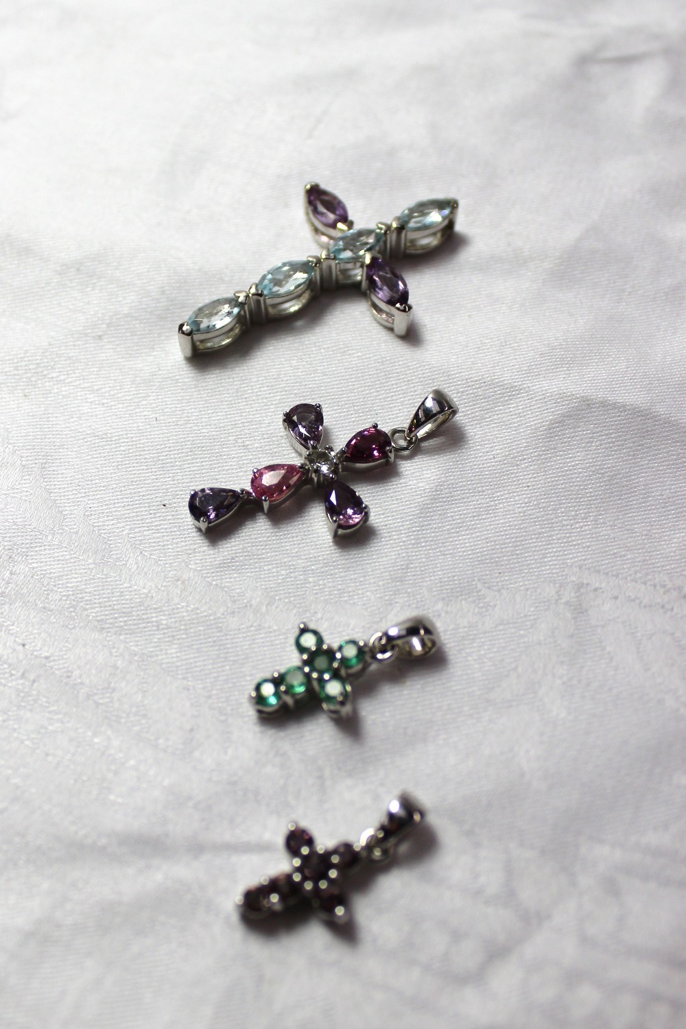 Three 9ct white gold and semi precious stone set crosses together with a silver example