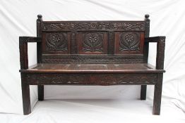 A 19th century oak settle, the carved panelled back decorated with flowers and leaves, the seat with