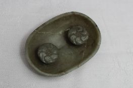 A Chinese jade dish of oval form with two carved raised buttons to the central section, 7cm wide