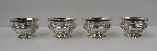 A set of four Edward VII silver open table salts of oval form decorated with scrolling leaves and