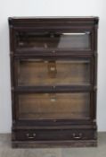 An oak section bookcase with a moulded dentil cornice above three beveled glass doors above a single