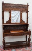 A 19th century Low Countries oak hall stand, with a leaf carved back, central mirror and shelf,