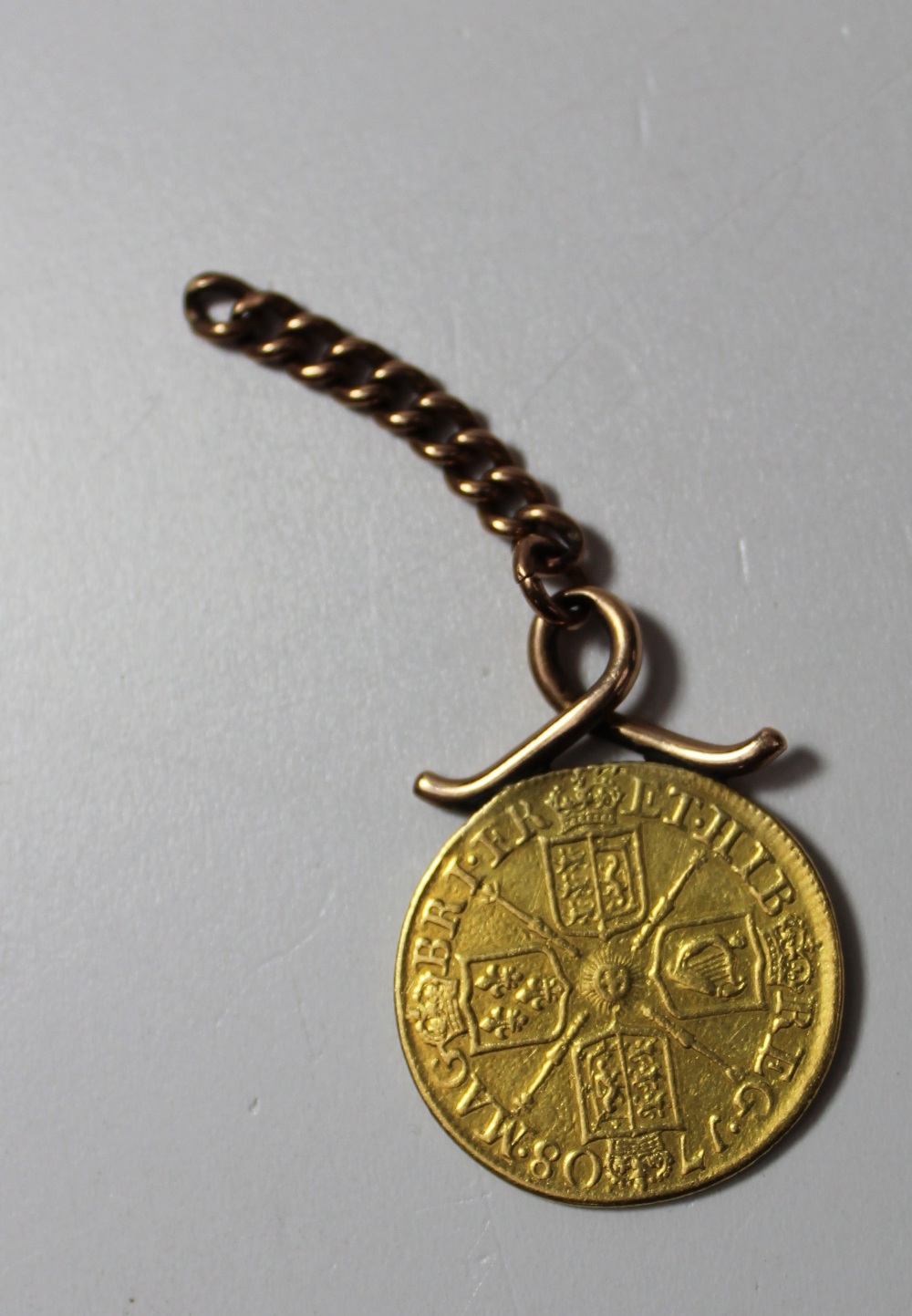 A Queen Anne gold Guinea dated 1708 mounted on a yellow metal ring and chain