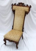 A Victorian walnut framed nursing chair, the carved T shaped back decorated with scrolls and leaves,