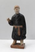 A Chinese statuette of a court attendant in terracotta with black and white pigment, possibly Ming