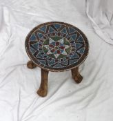 An African stool, the circular dished top inlaid with beads on four cylindrical legs, 33.5cm
