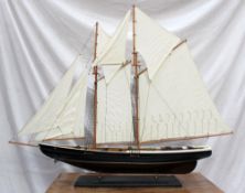 A wooden model of a pond yacht with two masts and eight sails on a stand, 109 cm wide by 97 cm high