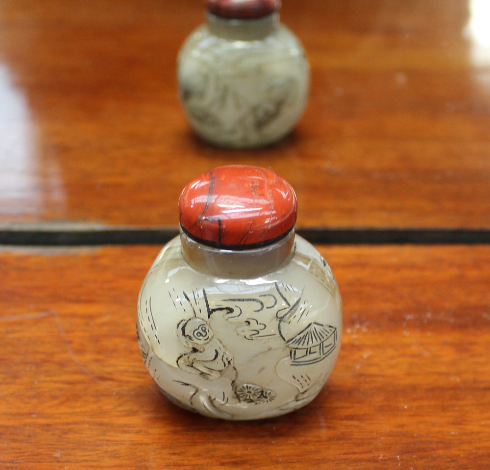 A hardstone snuff bottle, the lacquered domed top above a carved body depicting figures & monkeys, 7