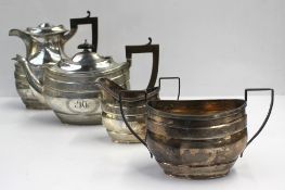 A George V silver four piece tea set of oval form with a Greek key pattern and initialled cartouche,