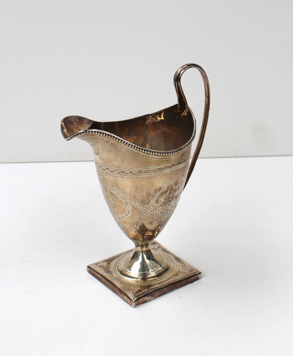 A George III silver helmet shaped cream jug with a beaded rim, the body decorated with swags of