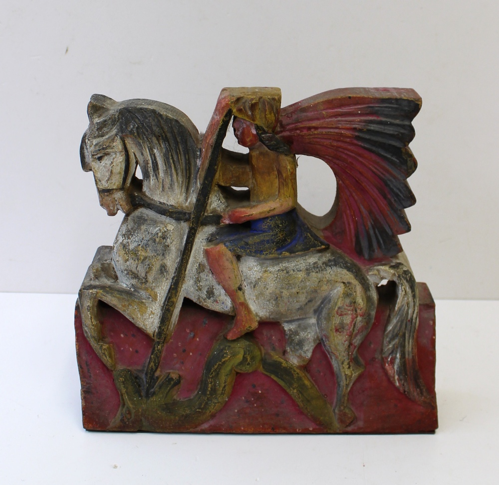A carved wooden door stop in the form of an American Indian on horseback spearing a dragon, 21 cm