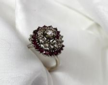 A diamond and ruby dress ring of swirling form set with nineteen brilliant cut diamonds and eighteen