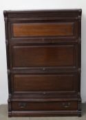 A mahogany sectional bookcase with three up and over panelled doors above a base drawer on a plinth,