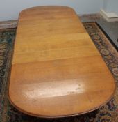 A late Victorian oak extending dining table, the oval top with two additional leaves on turned