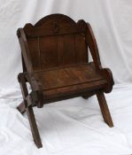 An oak Glastonbury chair, the back rail carved "Cymru Am Byth", 1893 and a harp, with a planked back