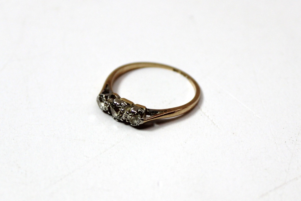 A three stone diamond ring, the old cut stones claw set in white metal to a yellow metal shank