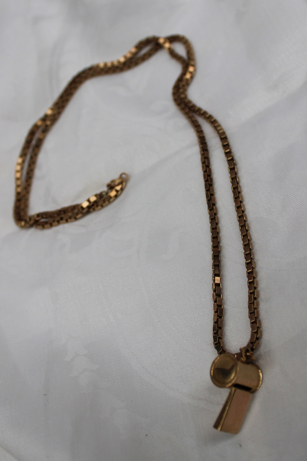 A 9ct yellow gold whistle pendant on a 9ct yellow gold box link necklace, approximately 23.5 grams