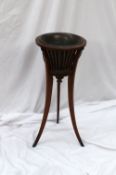An Edwardian mahogany jardiniere stand, the circular top with slat sides, lion masks and chain