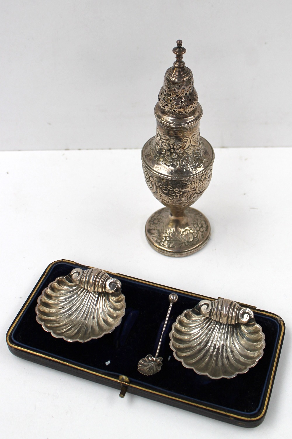 A George III silver sugar caster, the pierced domed cover above an urn shaped body embossed with