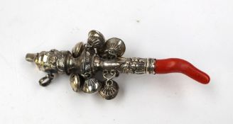 A white metal and coral rattle with a whistle and bells decorated with flower heads