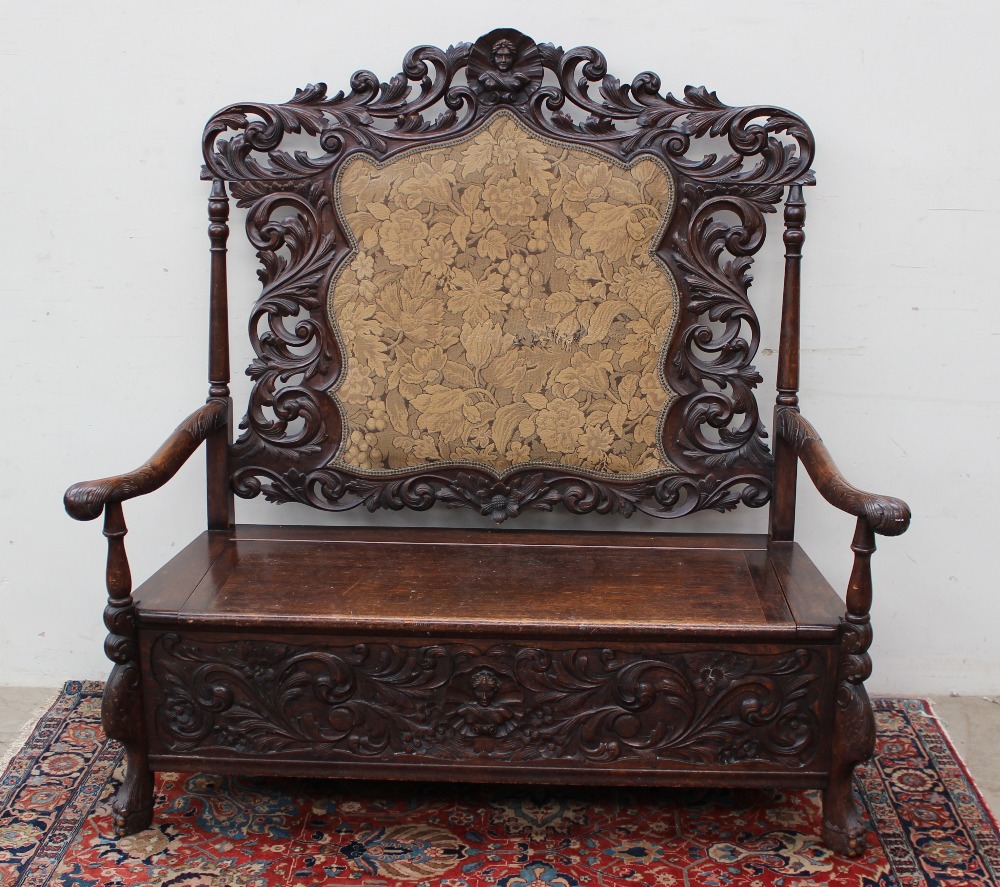 A 19th century Low Countries oak box settle, the back carved with a central shell and bust, carved